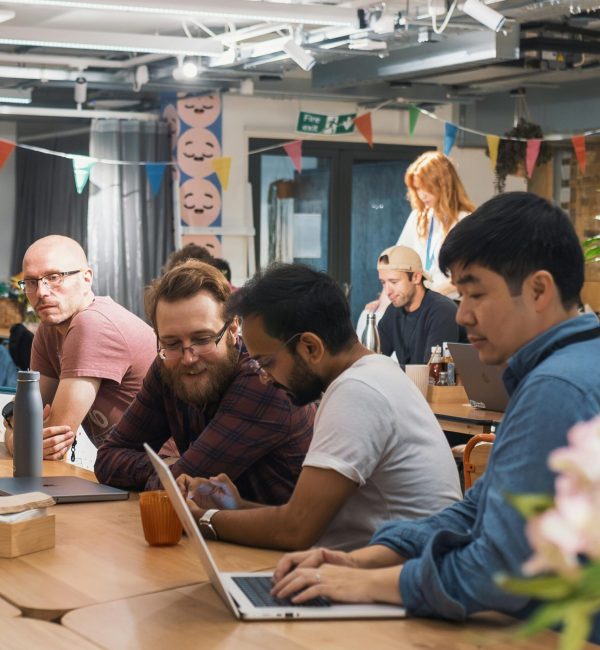 Group of professionals collaborating in a modern office space with laptops.